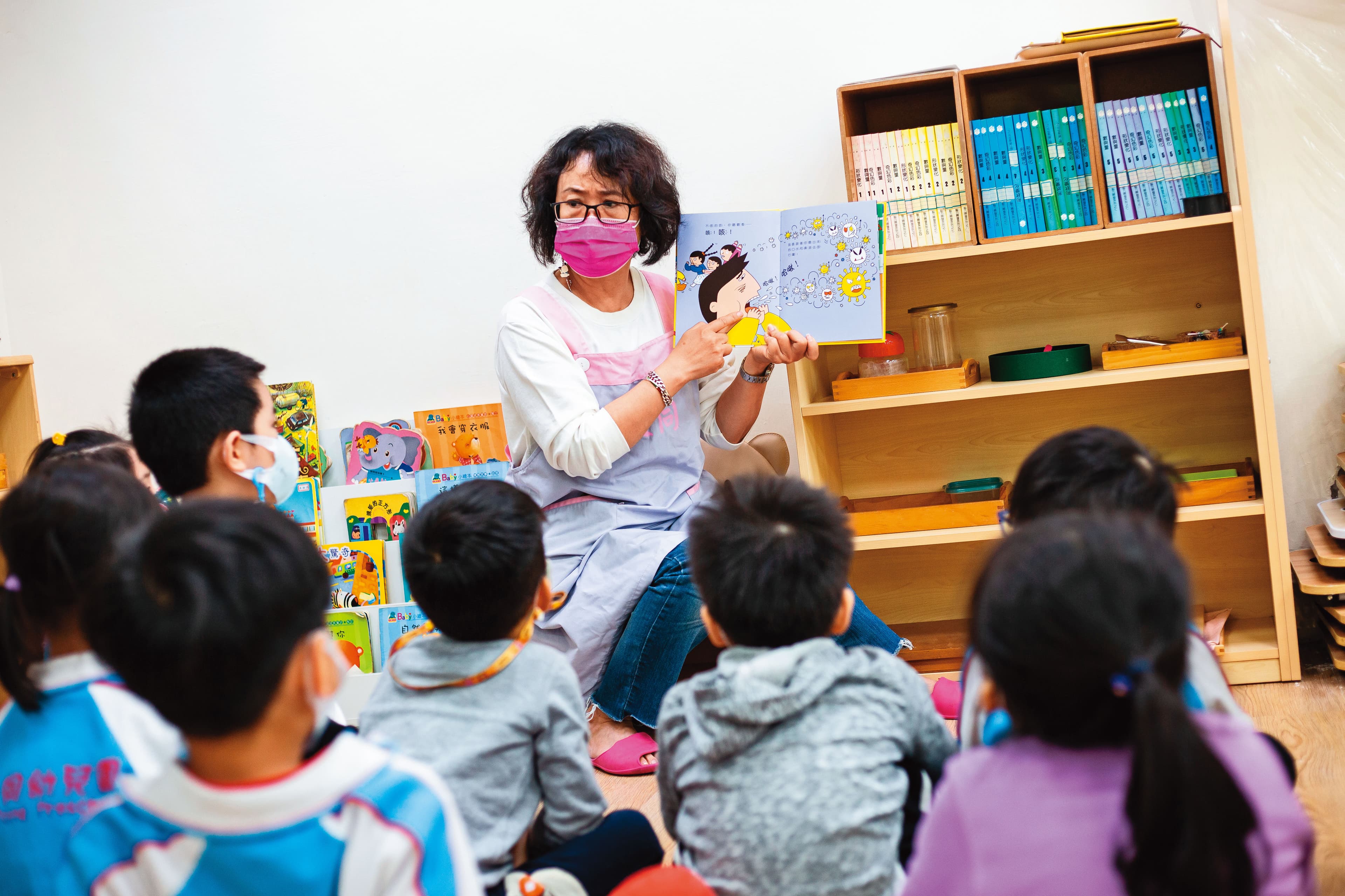 幼兒園老師透過繪本描述病毒的傳染途徑。