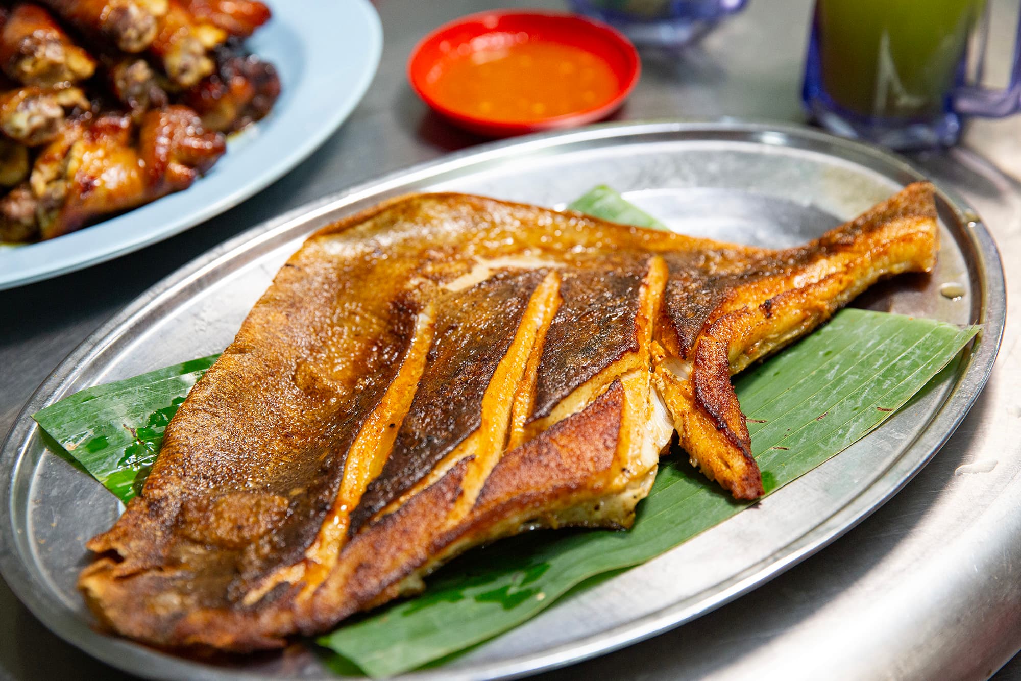 黃亞華的「燒蒲魚」選用新鮮魔鬼魚,裹上特製叁巴醬後以香蕉葉包裹炭烤,魚肉嫩滑多汁,帶有濃郁的辣香與炭火味。