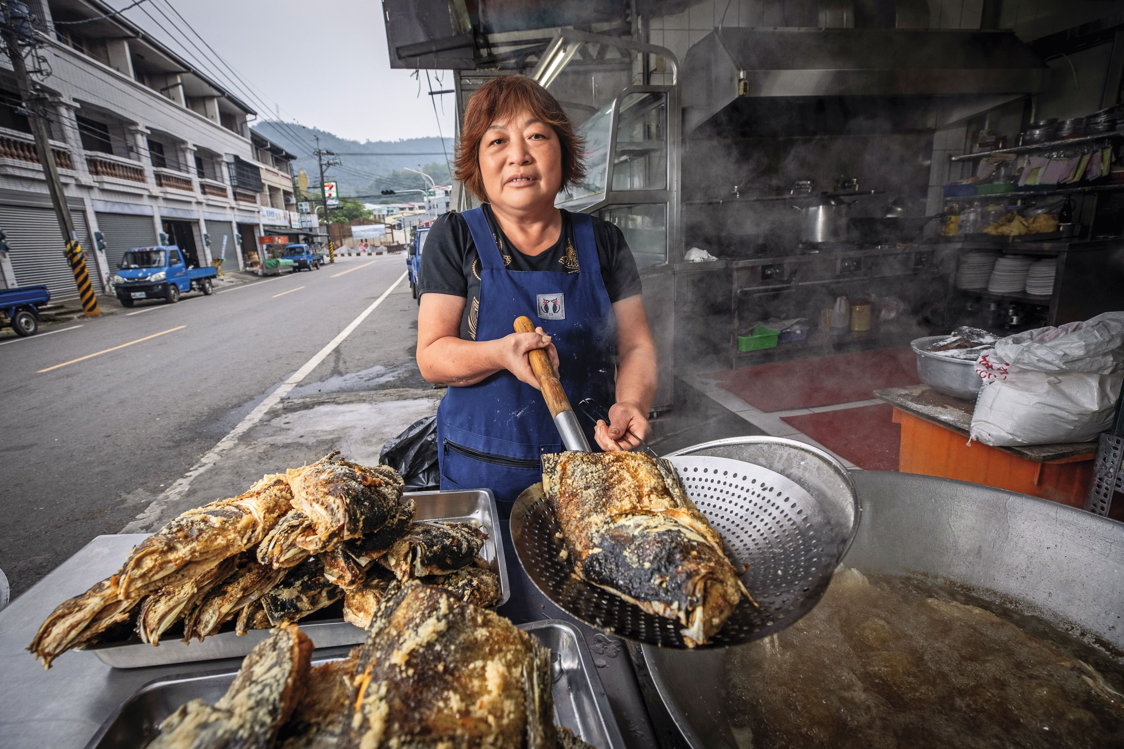 清晨5點多,砂鍋魚頭一條街仍冷清,江明苓隻身在店前馬路邊煮白斬雞、炸魚頭,10度低溫下卻大汗淋漓。