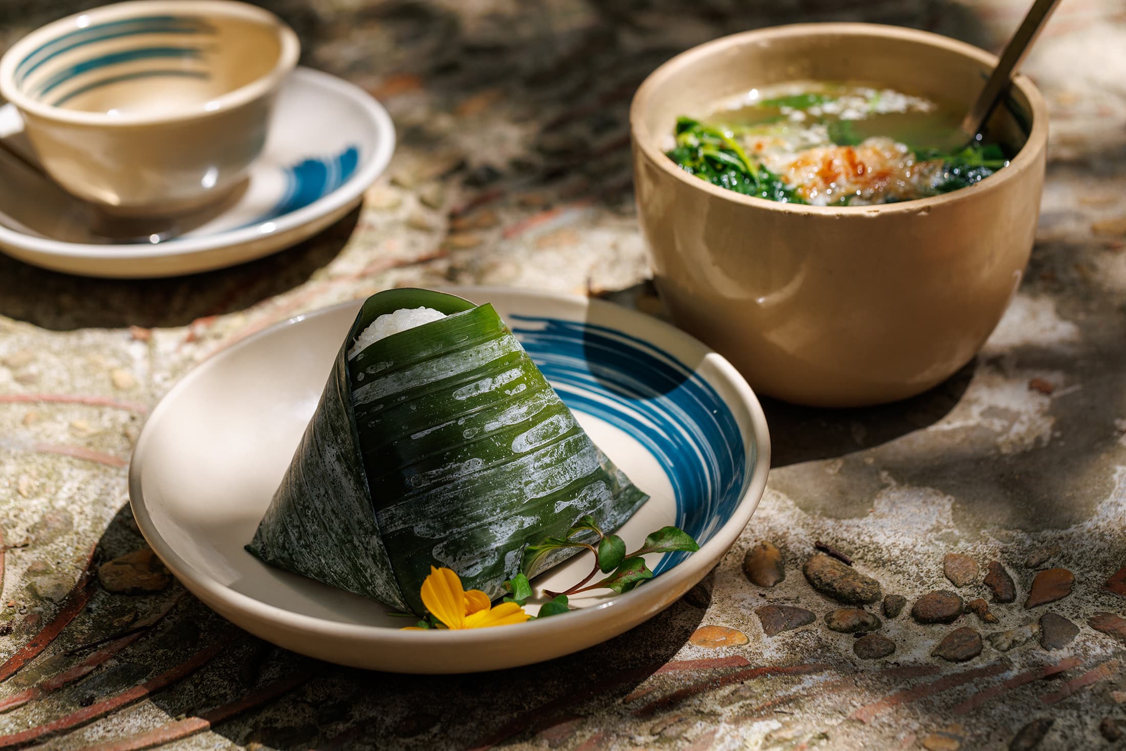 極具鄉村色彩的「芭蕉葉包飯」,將米飯與椰漿或香料拌勻,包在芭蕉葉中蒸煮出清新草香,拆開時香氣撲鼻。搭配茶桂村直送、清甜回甘的鮮綠蔬菜湯,是最道地的農家菜餚。
