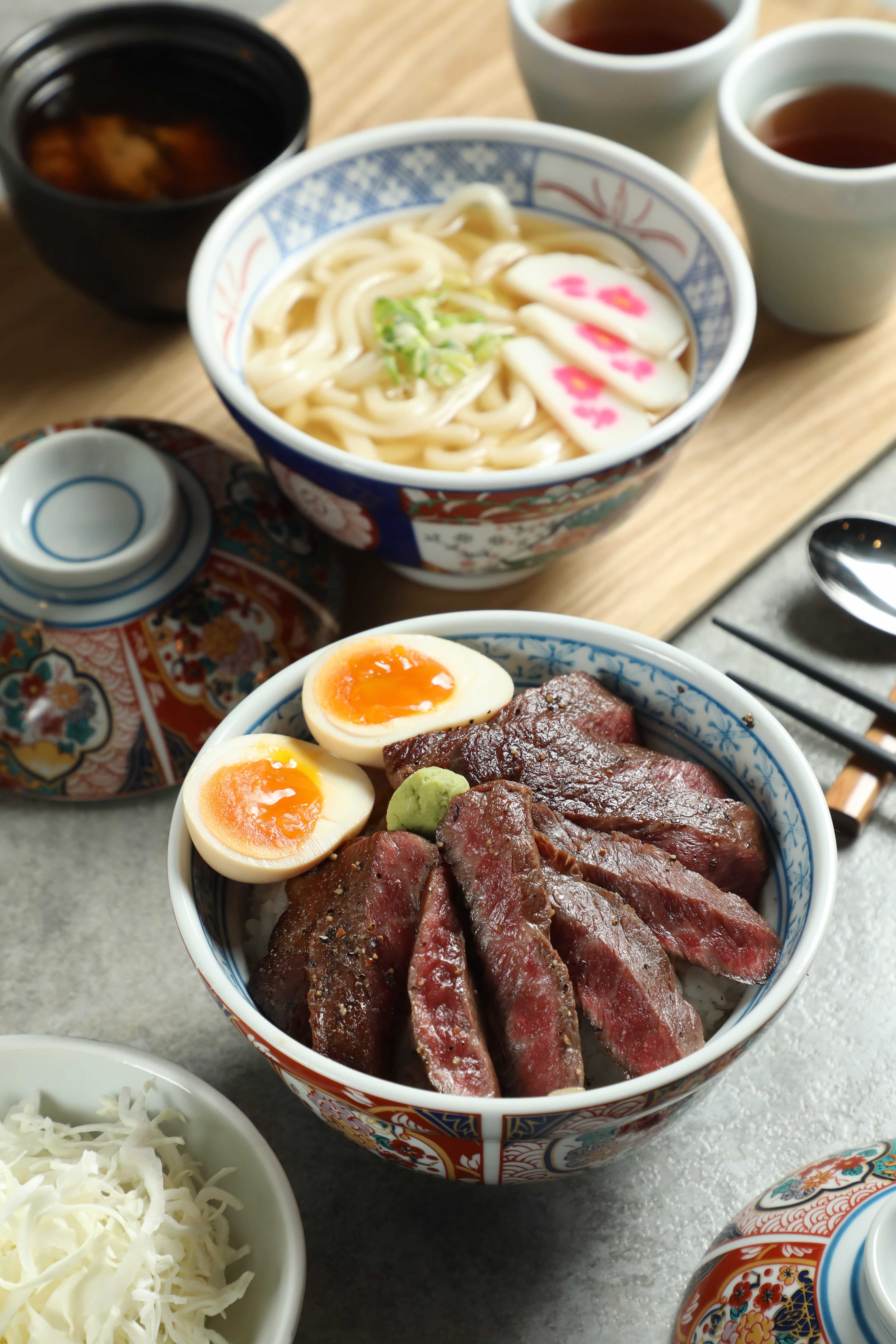 「和牛牛排丼」(前,600元/份)厚切和牛經炙烤後香氣四溢,呈現和牛的油脂風味;「出汁烏冬」(後,130元/份)以日式高湯襯托和牛鮮甜,Q彈烏龍麵吸附滿滿湯汁精華。