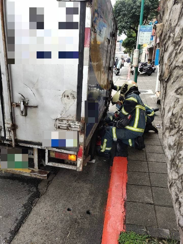 消防人員彎腰到車底要救阿嬤。(警方提供)