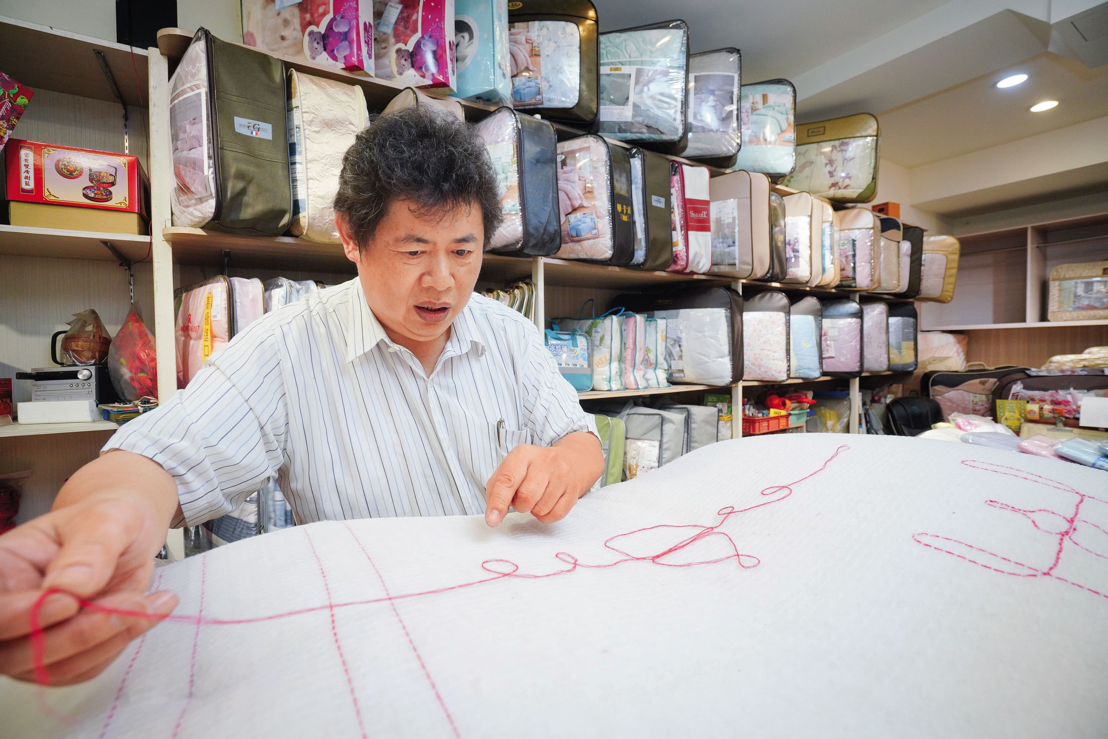 古代手工棉被行普遍沒有店名,師傅以自創商標識別。張寶仁示範祖傳「葫蘆」標誌如何編織。
